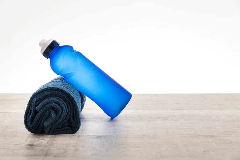 Zestaw akcesoriów sportowych: skakanka, mata do ćwiczeń, hantelki i gumki oporowe na drewnianej podłodze