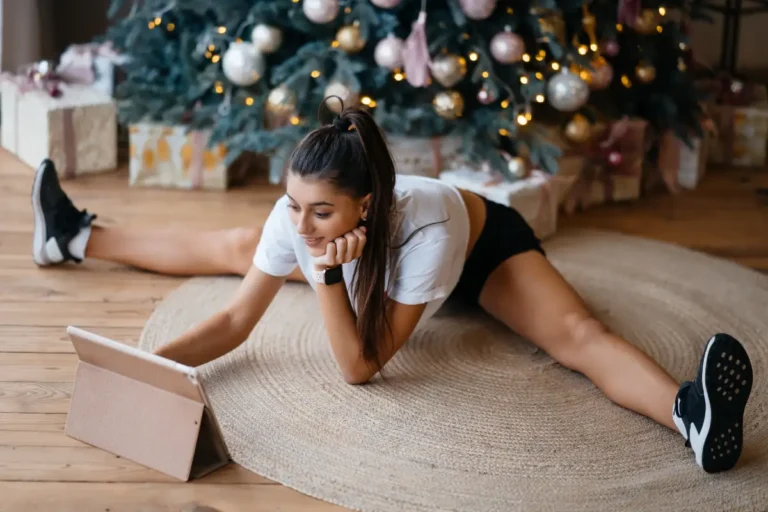 Kobieta ćwicząca na macie w domu, na tle świątecznej choinki – idealny trening w okresie Bożego Narodzenia
