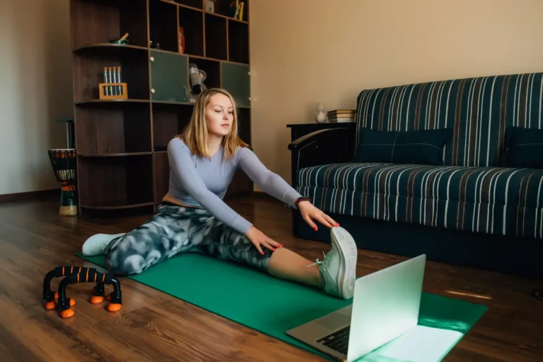 Kobieta trenująca w domu z akcesoriami fitness, takimi jak hantle, mata do ćwiczeń i gumy oporowe