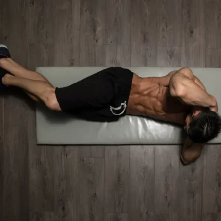 Młody chłopak trenuje w domu mięśnie brzucha stosując się do porad z ebooka: 30-dniowa Domowa Rewolucja: Prosty plan na spalanie tłuszczu i budowę formy