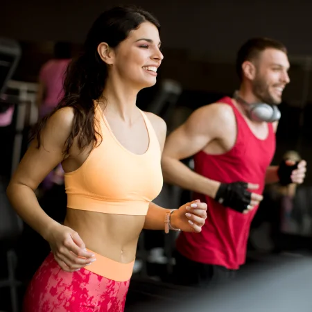 Młodzi ludzie trenują fitness czytając ebook z planami treningowymi akademii fitlle