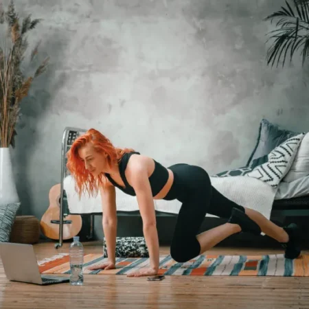 Młoda kobieta rozgrzewa się do treningu fitness i crossfit w swoim salonie.