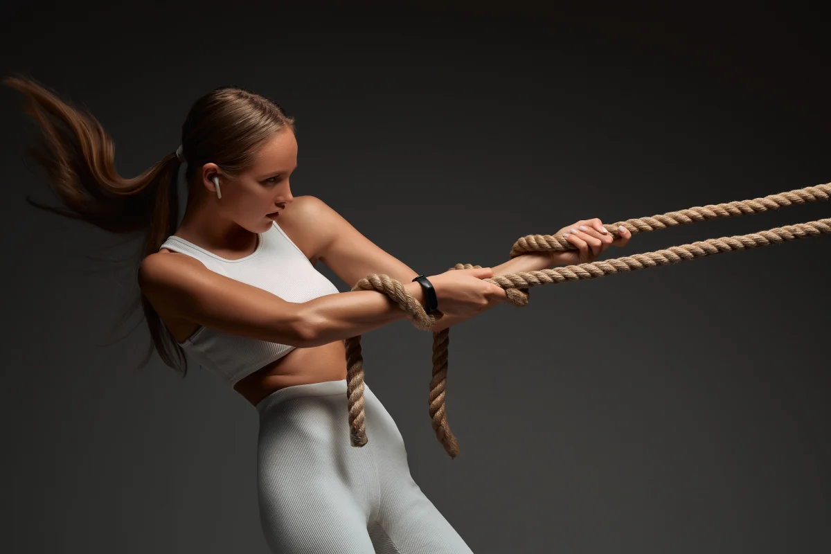 Kobieta przeciągająca linę podczas treningu crossfit i kalisteniki w domu – ćwiczenie funkcjonalne na siłę i wytrzymałość