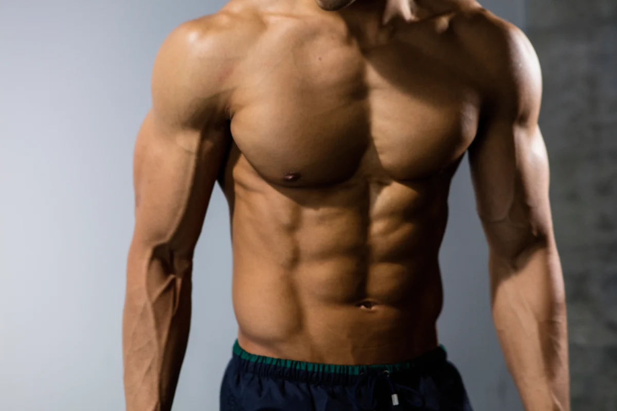 Młody mężczyzna z wyrzeźbionym sześciopakiem na brzuchu – efekty treningu i diety w domu