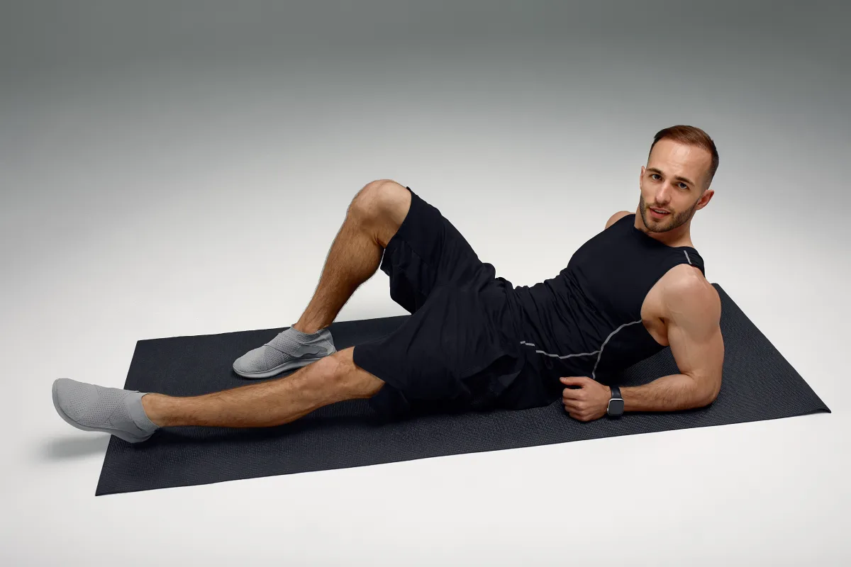 Dojrzały facet siedzi na macie do ćwiczeń w domu i odpoczywa po intensywnym treningu hiit