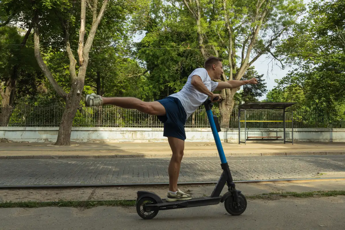 Młody chłopak jedzie na hulajnodze elektrycznej na jednej nodze