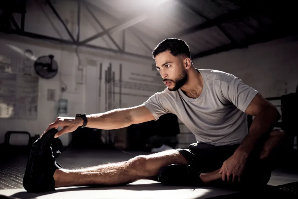 młody chłopak robi rozgrzewkę przed treningiem siłowym w domu bez sprzętu